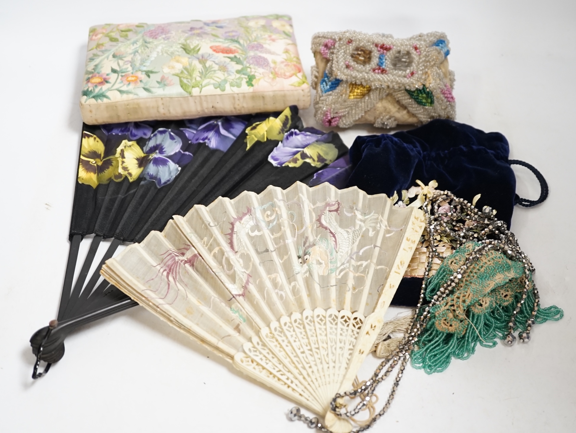 A Chinese 1920’s boxed carved bone and silk embroidered dragon fan, a larger European pansy decorated fan, a bead worked basket, a mat, two cut steel necklaces, an embroidered pin cushion, an evening bag and a misers pur